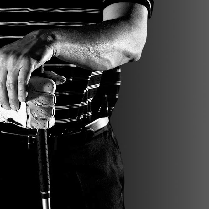 close up of a golfer with both of his hands on the golf club. One hand has a golf glove on.